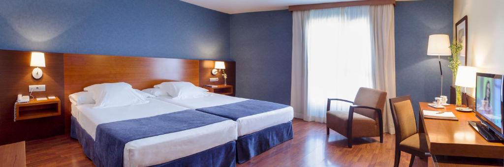 a hotel room with a large bed and a desk at Hotel Torre de Sila in Tordesillas