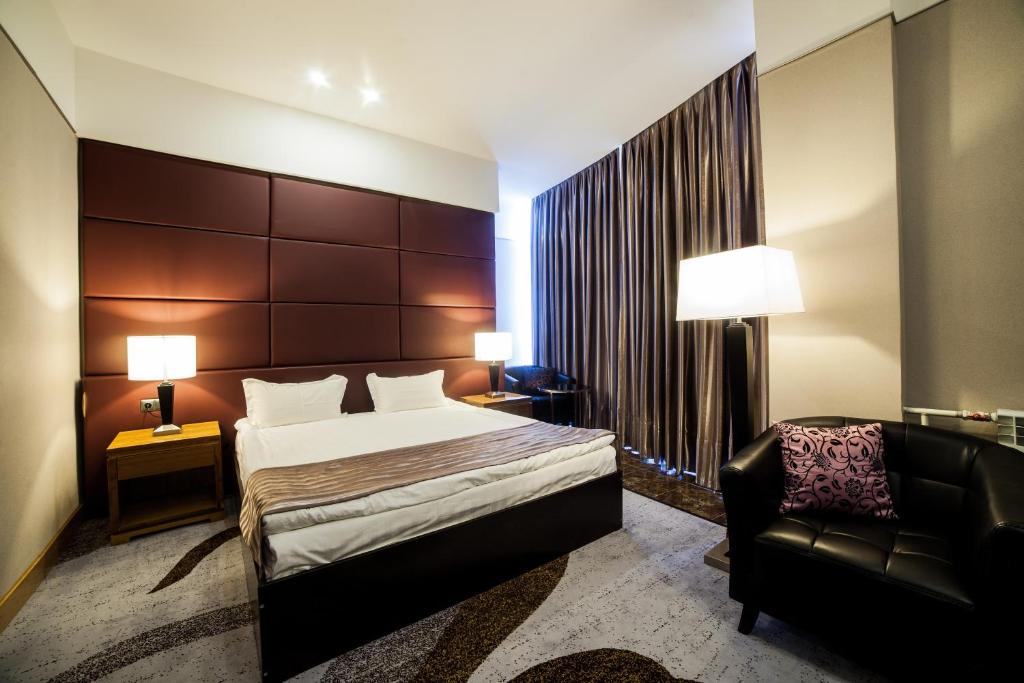Habitación de hotel con cama y silla en Absolute Hotel, en Astana