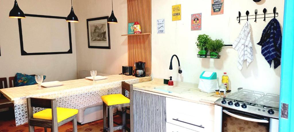 a kitchen with a counter with yellow chairs in it at Casa aconchegante perto da praia in Guarujá