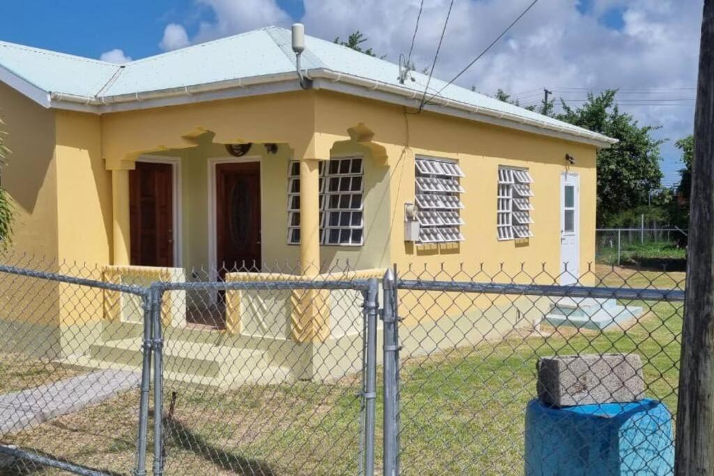 a yellow house behind a fence at Cozy Cottage in Woods