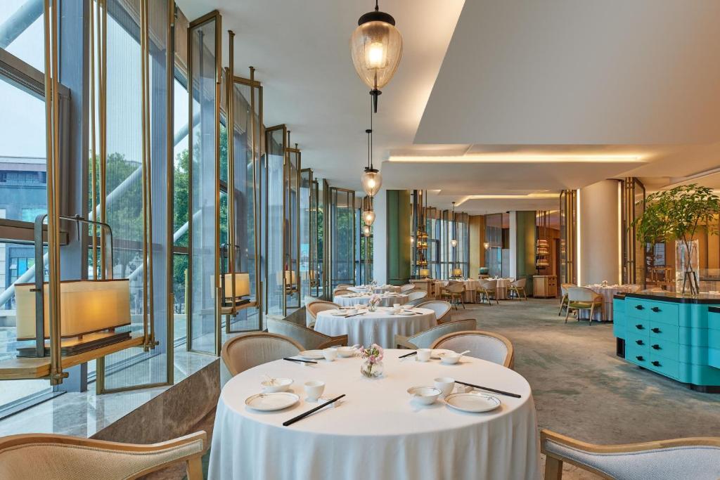 a restaurant with tables and chairs and large windows at Courtyard by Marriott Yangzhou in Yangzhou