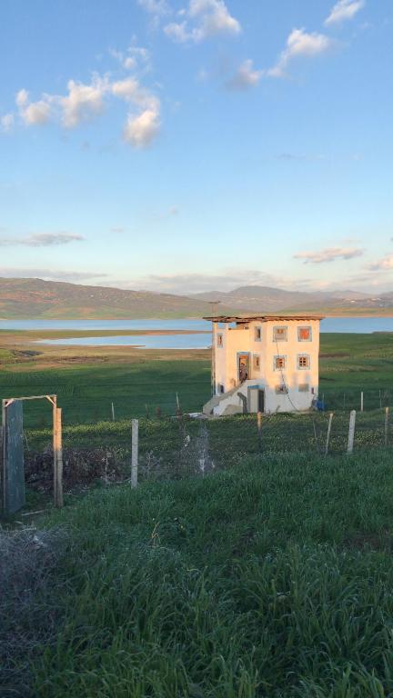 a building in the middle of a field with a fence at Lala Elyacout in Azzaba