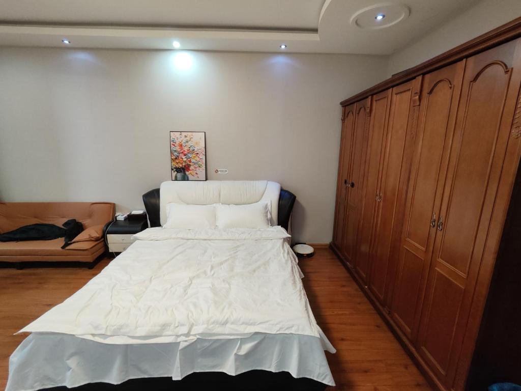 una camera da letto con un letto bianco e un divano di 博博家精品民宿 a Harbin