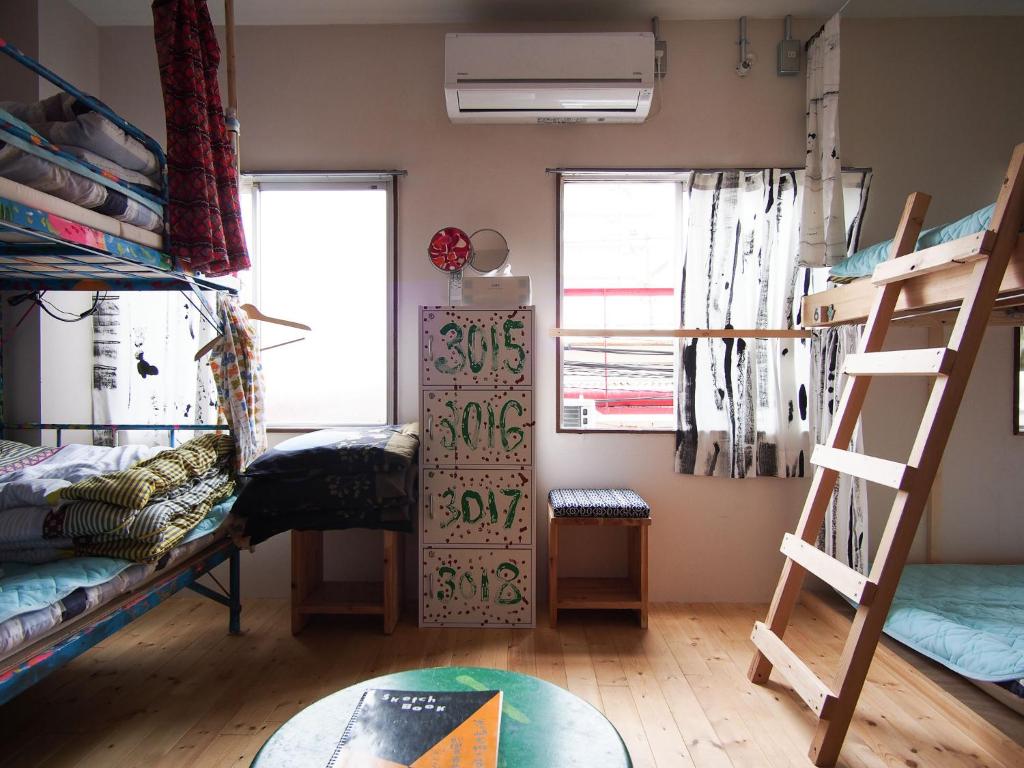 a dorm room with bunk beds and a ladder at Kamagasaki University of the Arts Cafe Garden Guest House aka Cocoroom in Osaka