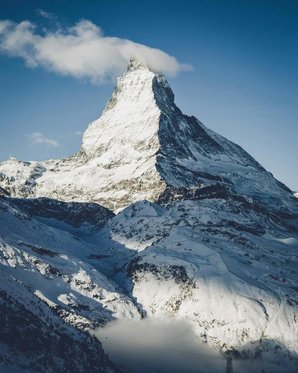 a mountain covered in snow with a sky at SCHLOSS Zermatt - CBD & Adaptogenic Spa and Sport Hotel in Zermatt