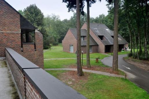 - une vue sur une maison avec une clôture et des arbres dans l'établissement Domein Hengelhoef, à Aan de Wolfsberg