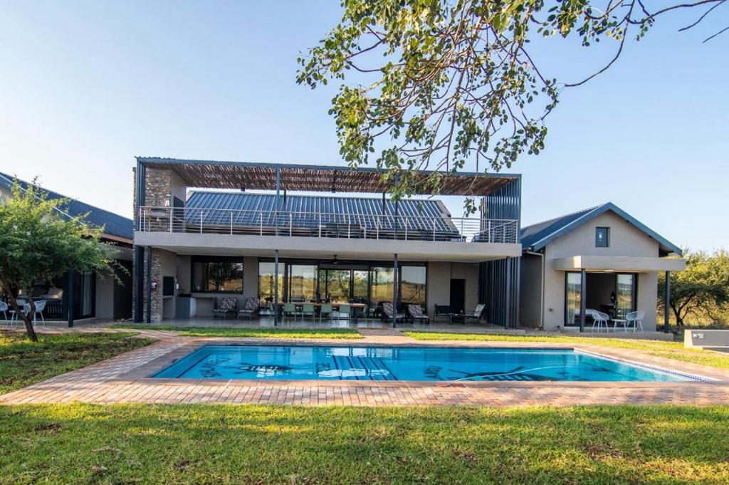 an exterior view of a house with a swimming pool at Sihlangu Lodge in Marloth Park