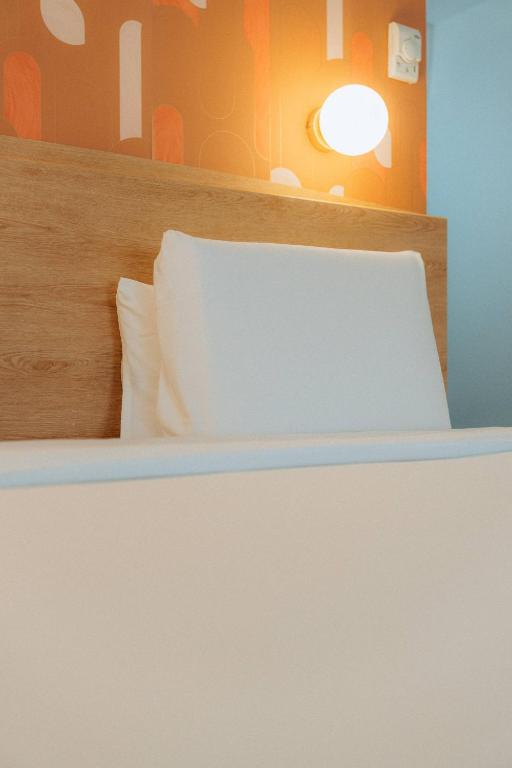 a white bed with a wooden headboard and pillows at Kyriad Cannes - Mandelieu in Cannes