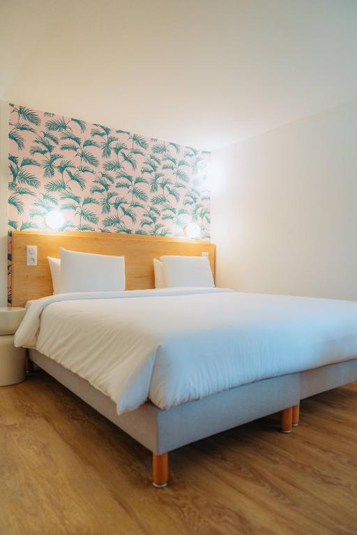 a bedroom with a large bed with a floral headboard at Kyriad Cannes - Mandelieu in Cannes