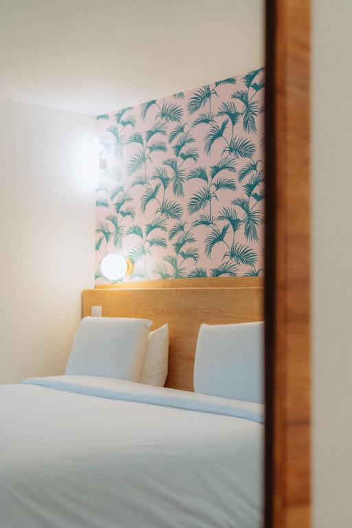a reflection of a bedroom with a bed and a wall at Kyriad Cannes - Mandelieu in Cannes