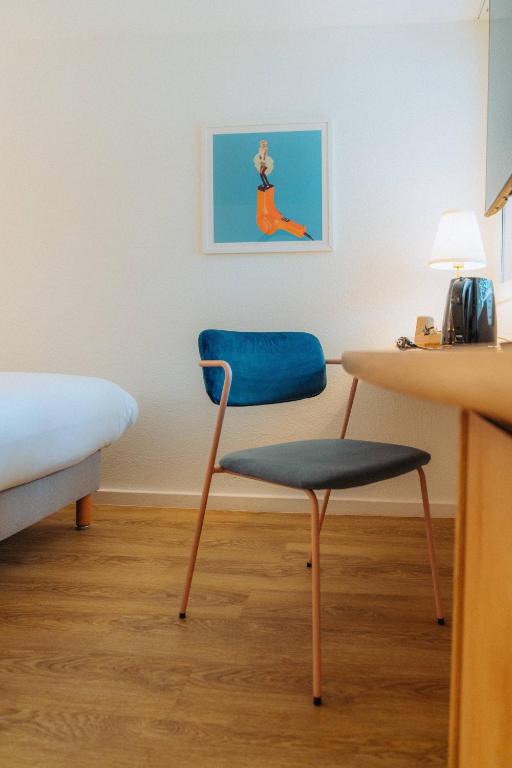 a blue chair and a table in a room at Kyriad Cannes - Mandelieu in Cannes