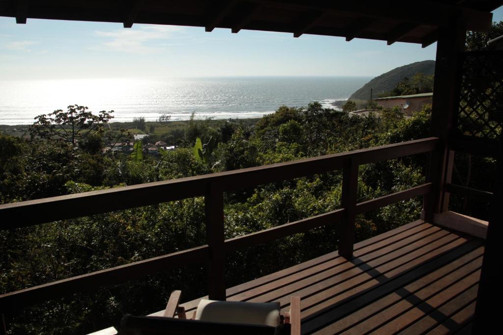 a view of the ocean from a porch with a bench at Bangalore Suites in Garopaba