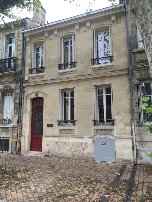 an old house with a red door and windows at La Canopée in Bordeaux