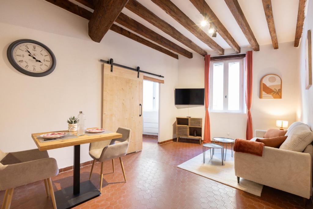 a living room with a table and a clock on the wall at Le Nostradamus - Hypercentre - Clim - Wifi in Saint-Rémy-de-Provence