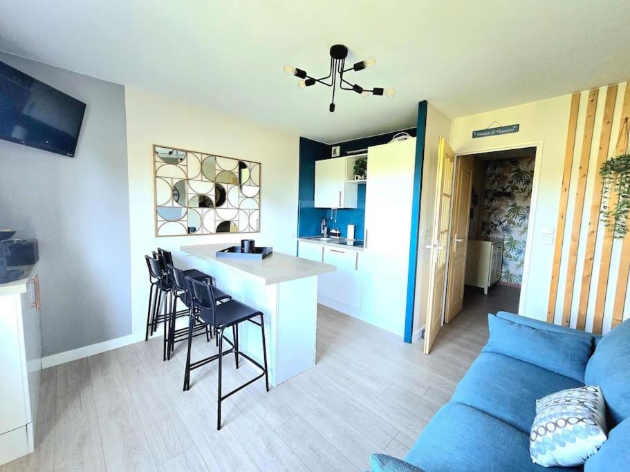 un salon avec un canapé bleu et une cuisine dans l'établissement Appart cosy - terrasse - clim - piscine, à Roquebrune-sur Argens