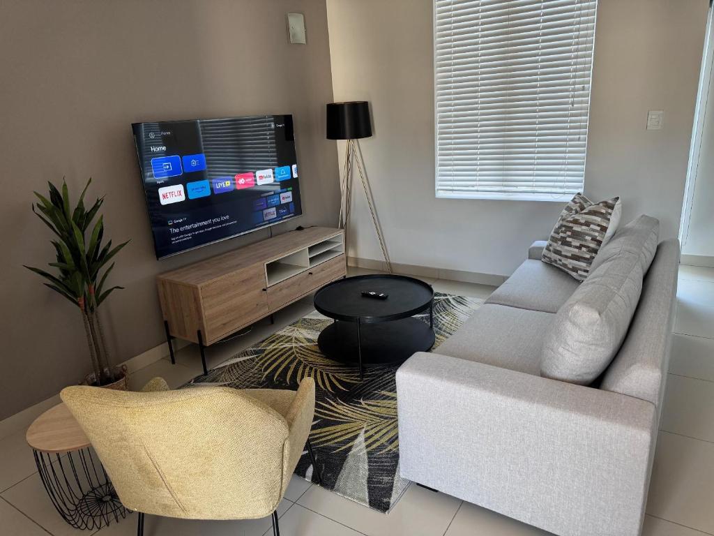 Una sala de estar con un sofá y un televisor de pantalla plana. en Beautifully furnished loft apartment in central Durbanville, en Durbanville