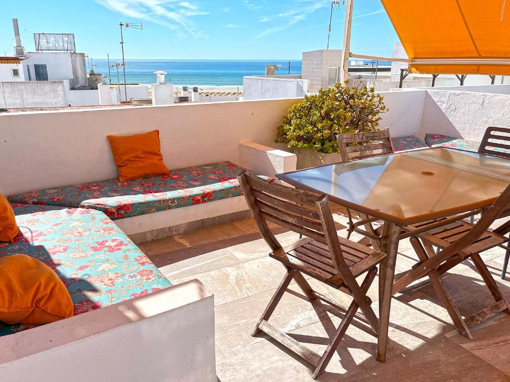 stół i krzesła na balkonie z widokiem na ocean w obiekcie Baluarte Conil town house with roof terrace and sea view in Barrio de los Pescadores w mieście Conil de la Frontera