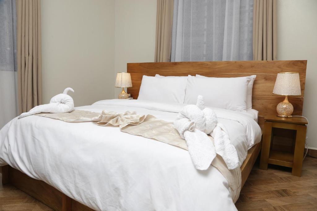 Una cama con dos toallas y dos pájaros rellenos. en Diamond Delight Boutique Hotels, en Moshi