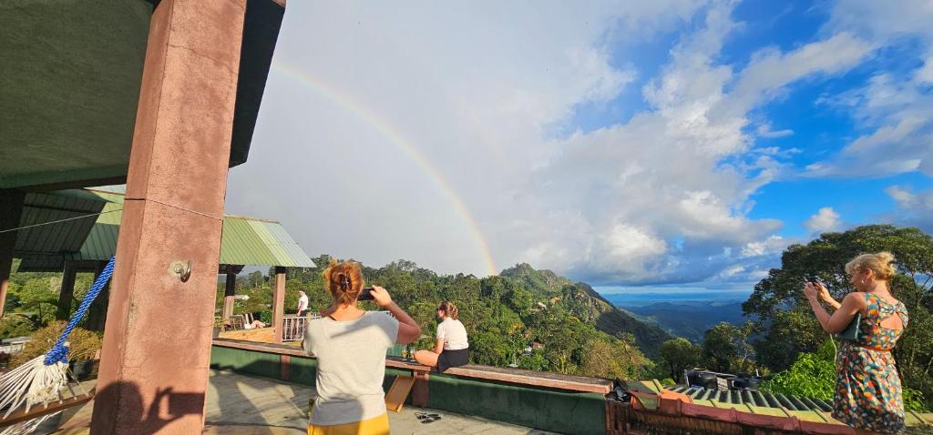 a woman taking a picture of a rainbow at Hilltop Guest House in Ella