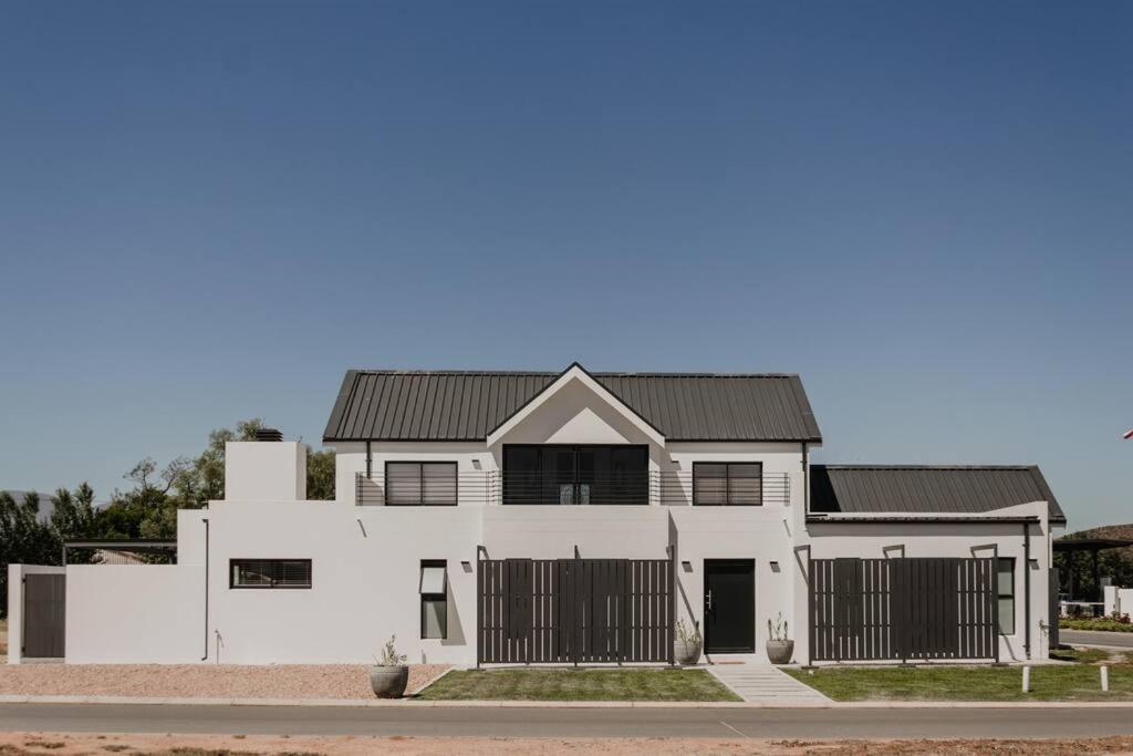 a white house with a black roof at Albatross Lodge - Silwerstrand Golf and River Estate in Robertson
