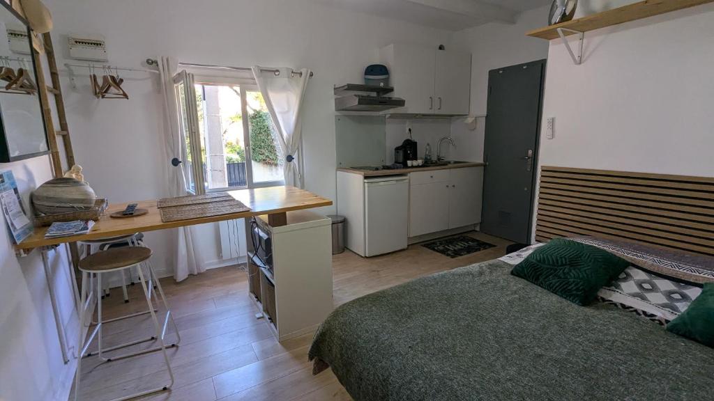 une chambre avec un lit et un bureau et une cuisine dans l'établissement STUDIO avec PARKING TOUT A PIED et CALME, à Bandol