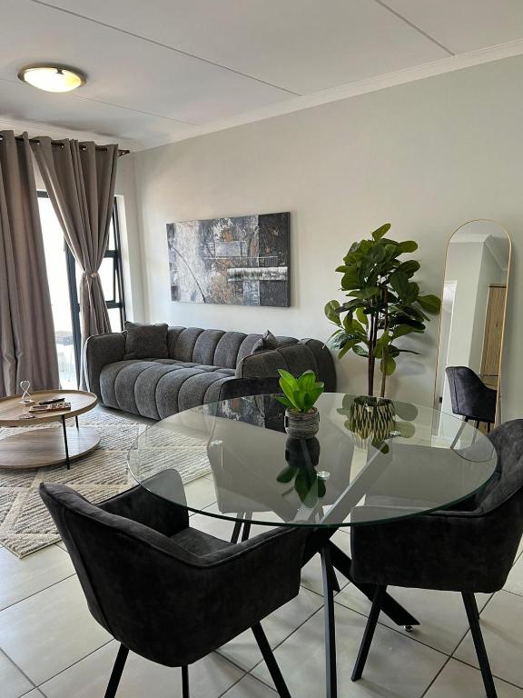 a living room with a glass table and black chairs at Cozy home in Pretoria