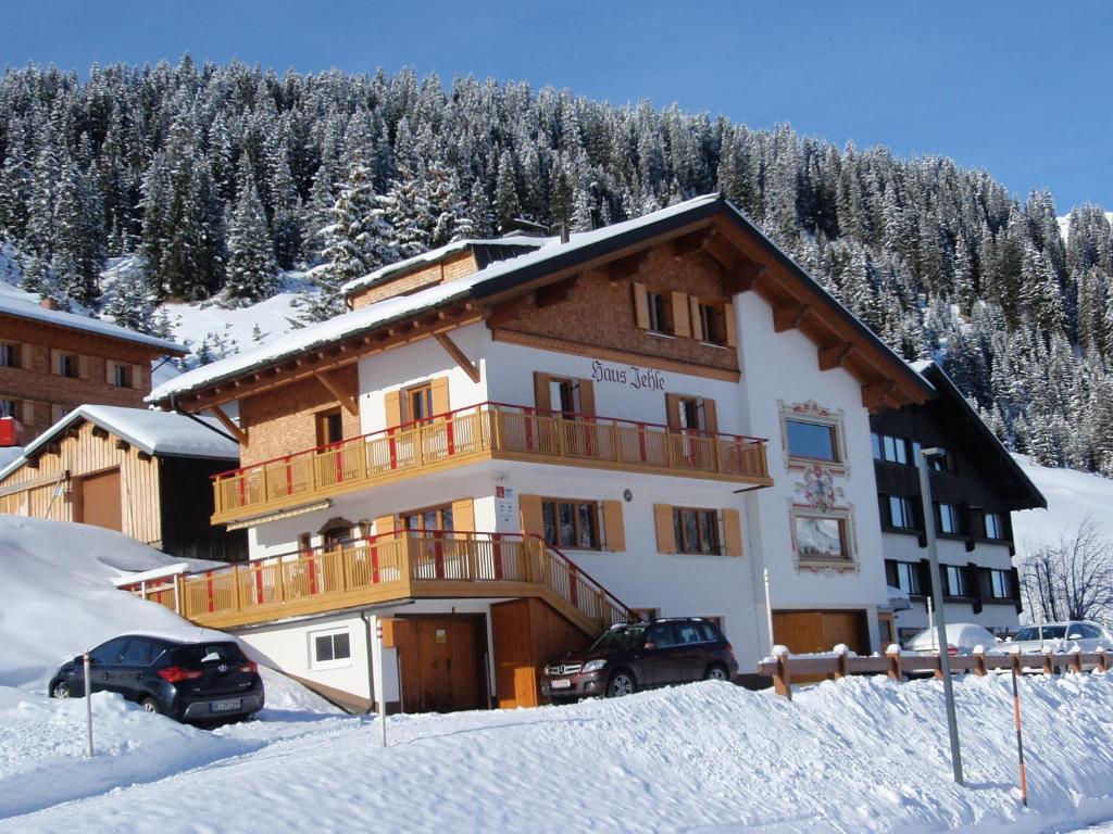 un bâtiment dans la neige avec des voitures garées devant dans l'établissement Haus Jehle, à Lech am Arlberg