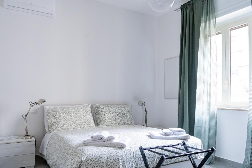 een witte slaapkamer met een bed met handdoeken erop bij LemonHouse in Napels