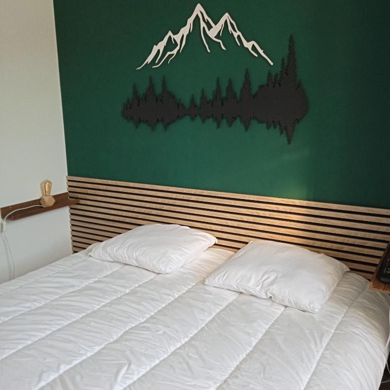 - un lit avec deux oreillers devant un mur vert dans l'établissement Appartement Centre Ville MONT DORE Vacances et Week-End Classé 3 Etoiles, à Le Mont-Dore