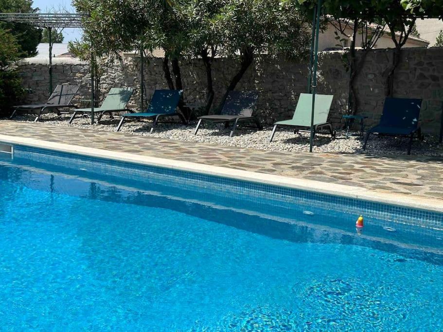 a swimming pool with blue chairs and a swimming pool at L'Olivette in Aubenas