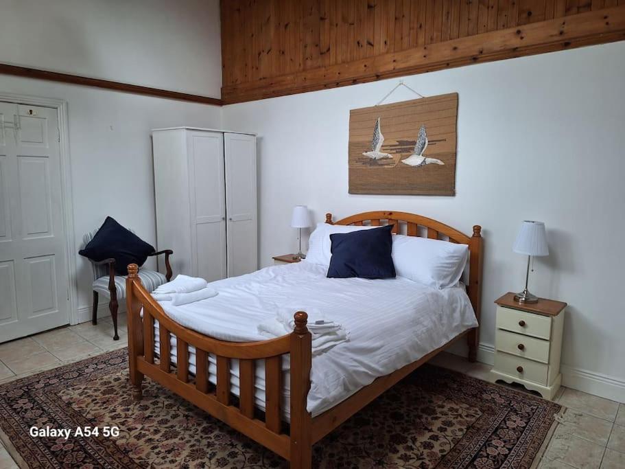 Schlafzimmer mit einem Holzbett mit weißer Bettwäsche und blauen Kissen in der Unterkunft The Stables in Aglish