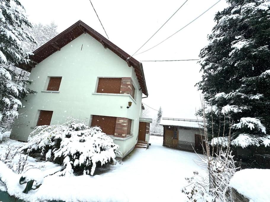 a house covered in snow with trees in front of it at Gîte de Pipala in Mittlach
