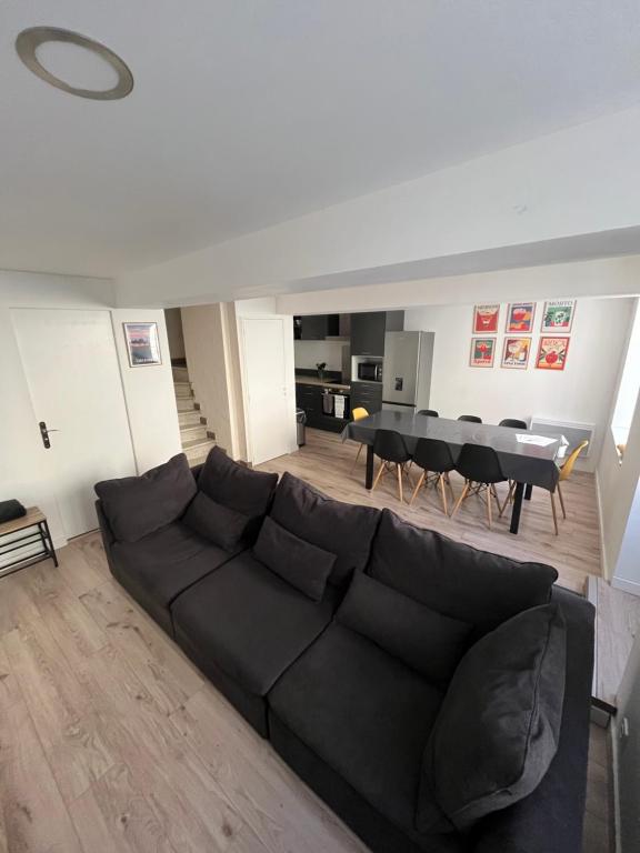 ein Wohnzimmer mit einer schwarzen Couch und einem Tisch in der Unterkunft La Maison du Roi Arthur in Carcassonne