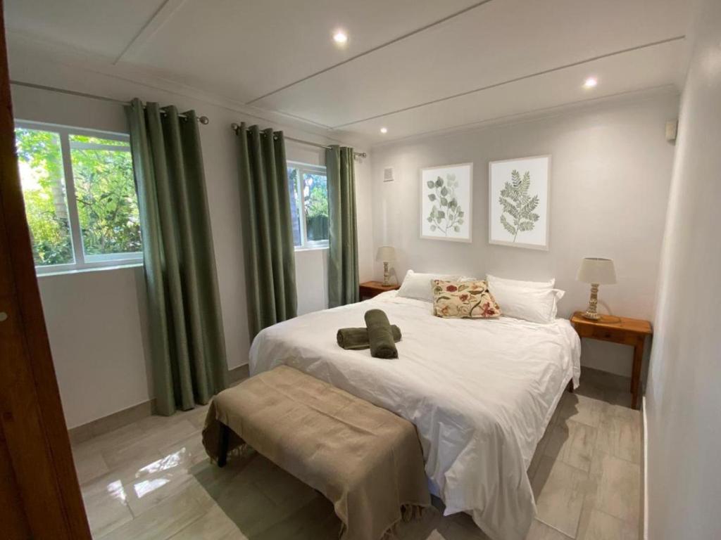 een slaapkamer met een groot wit bed en groene gordijnen bij Birdsong Cottage in Swellendam