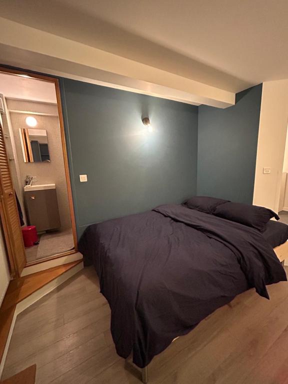 une chambre avec un lit avec un mur bleu dans l'établissement Villa Ribot, à Paris