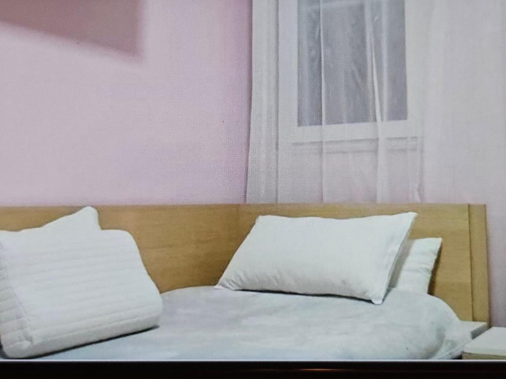 a bed with white sheets and pillows next to a window at Marea Resort in Golem
