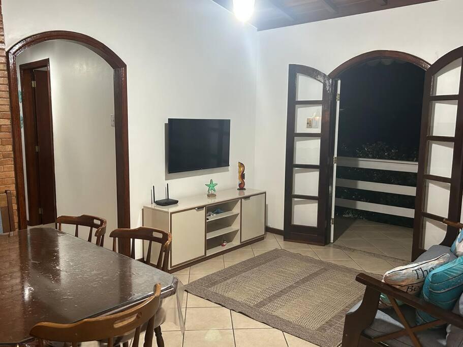 a living room with a table and a flat screen tv at Casa toda Equipada 900 metros da Lagoa, próxima as praias in São Pedro da Aldeia