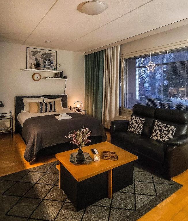 a bedroom with a bed and a couch and a table at Lakeside Serenity Lutakko - sauna, parking in Jyväskylä