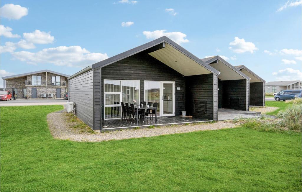 a small black house with a grass yard at Two-Bedroom Holiday Home Ringkøbing 04 in Søndervig