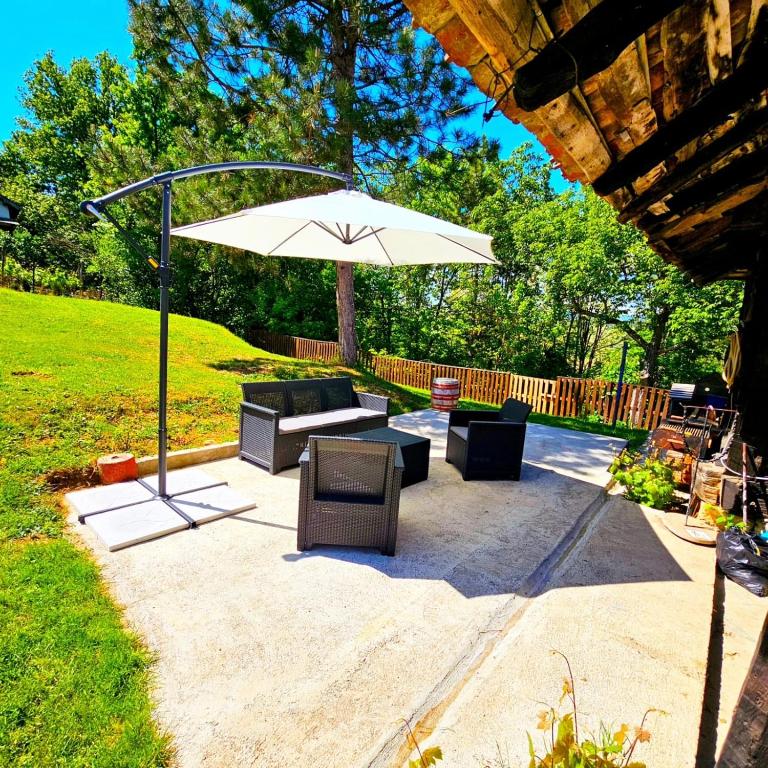 a patio with a table and an umbrella at Topola vikendica in Topola