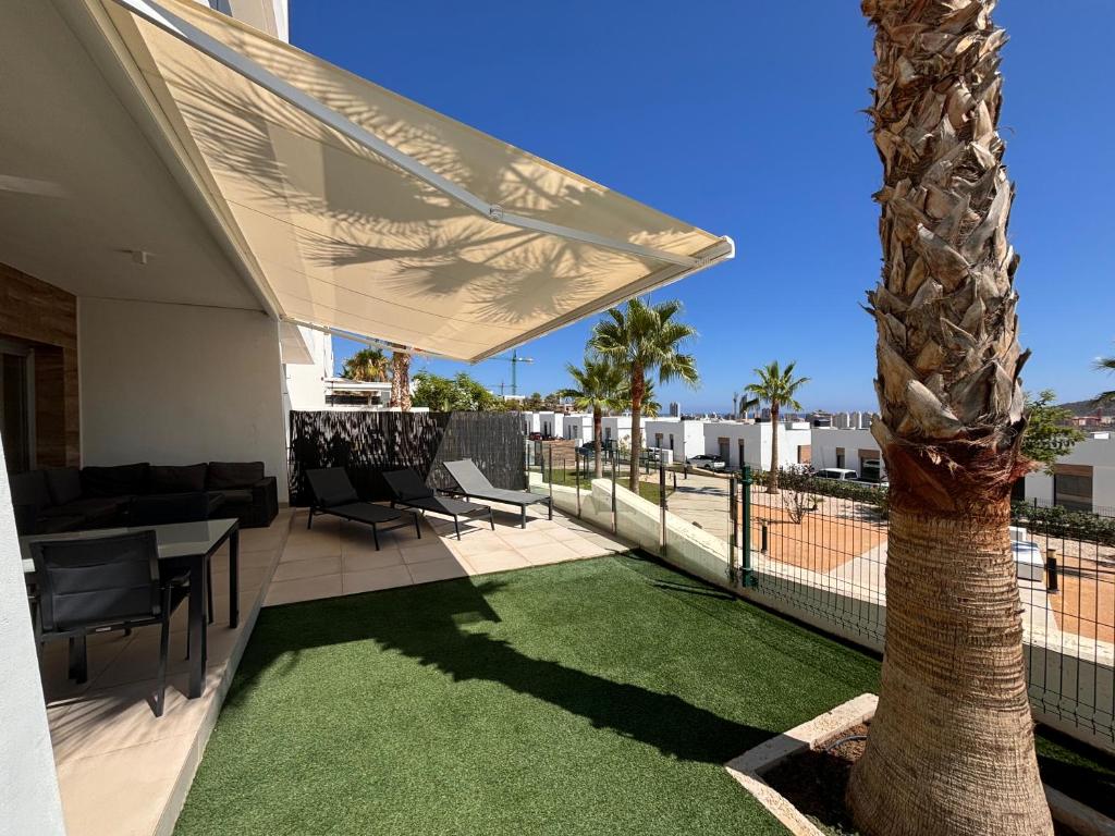 eine Terrasse mit einer Palme, einem Tisch und Stühlen in der Unterkunft Martormar in Finestrat