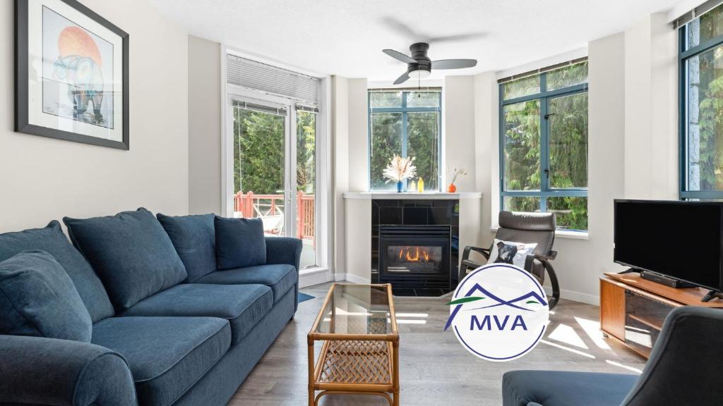 a living room with a blue couch and a fireplace at Alpenglow Lodge Bear Wonder One Bedroom by MVA in Whistler