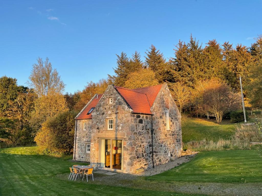an old stone building with a red roof on a field at Stunning Rural Mill House nr beach and harbour in Banff