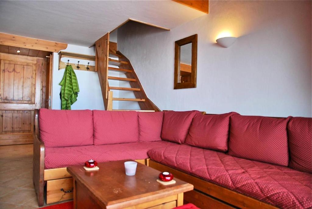 - un canapé rouge dans le salon avec un escalier dans l'établissement Résidence Saint Bernard G - SAINT BERNARD B16 MAE-9991, à Arc 1800