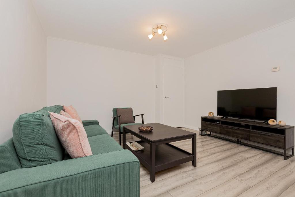 a living room with a green couch and a table at 2BR with parking, Mill Hill, NW London, 10min Tube in Mill Hill