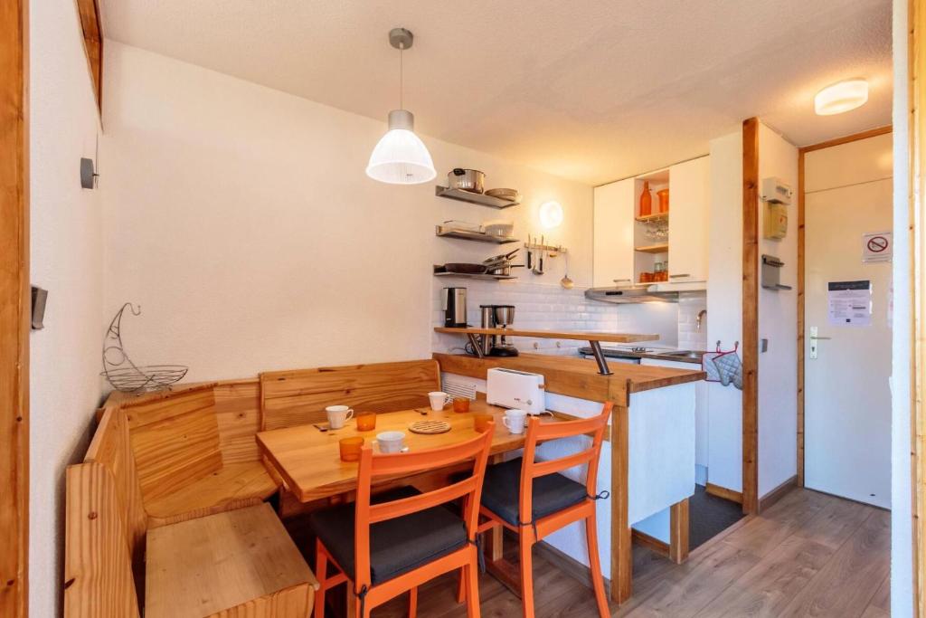 une cuisine et une salle à manger avec une table et des chaises en bois dans l'établissement Résidence Le Trompe L'oeil - TROMPE L’ŒIL 09 MAE-0421, à La Plagne Tarentaise