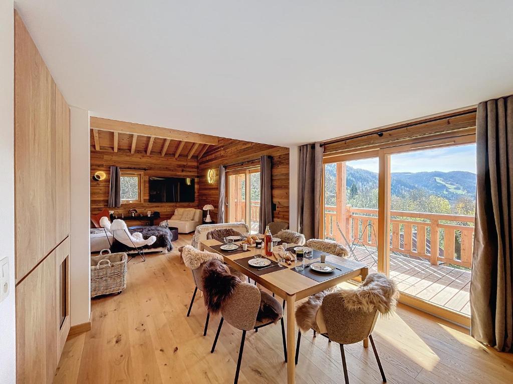 - un salon avec une table, des chaises et une grande fenêtre dans l'établissement Clos darsene - Les Gets - Proche centre, aux Gets