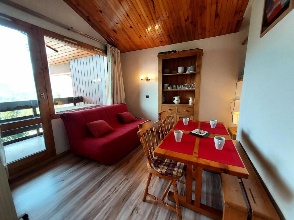 un salon avec une table et un canapé rouge dans l'établissement Résidence Le Trompe L'oeil - TROMPE L’OEIL 13 MAE-0741, à La Plagne Tarentaise