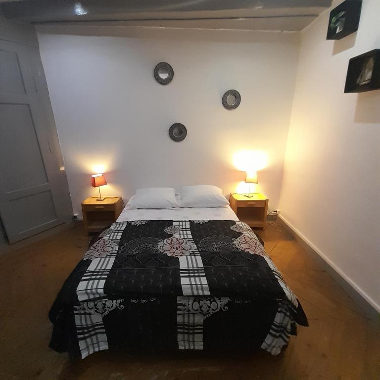 - une chambre avec un lit et deux lampes sur deux tables dans l'établissement La Hall, à Thiers