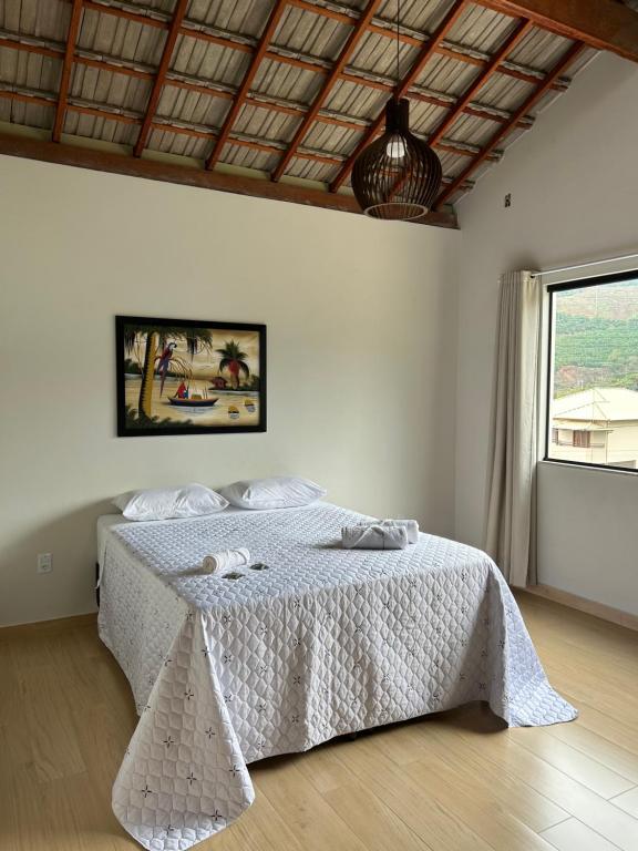 ein Schlafzimmer mit einem Bett mit einer weißen Bettdecke und einem Fenster in der Unterkunft Castelo fort in Caparaó Velho